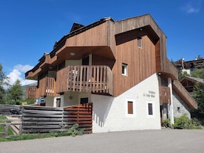 Ein mehrstöckiges Holzhaus mit Balkonen, einem Steinsockel und einem Schild, das es als Wohnhaus kennzeichnet.