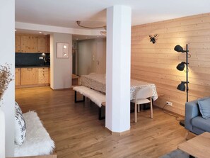 Ein modernes Interieur mit Essbereich, einer Couch und einer Holzwand mit Wandleuchten.
