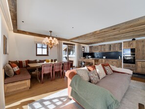 A modern interior with a dining area, kitchen, and seating space. - Val d'Isère - Spacious 109 m² Chalet for 8 (Val-d'Isère)
