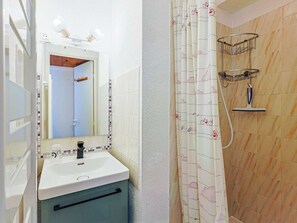 Ein Badezimmer mit Waschbecken, Spiegel, Dusche und Handtuchhalter.