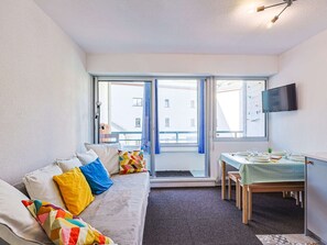 Ein gemütlicher Raum mit einer Couch, einem Esstisch und einem Fernseher.