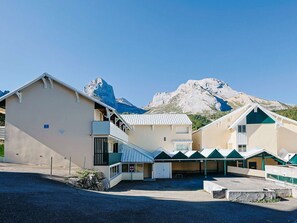 Ein Gebäude mit flachem Dach, einer überdachten Eingangspartei und einem Berg im Hintergrund.