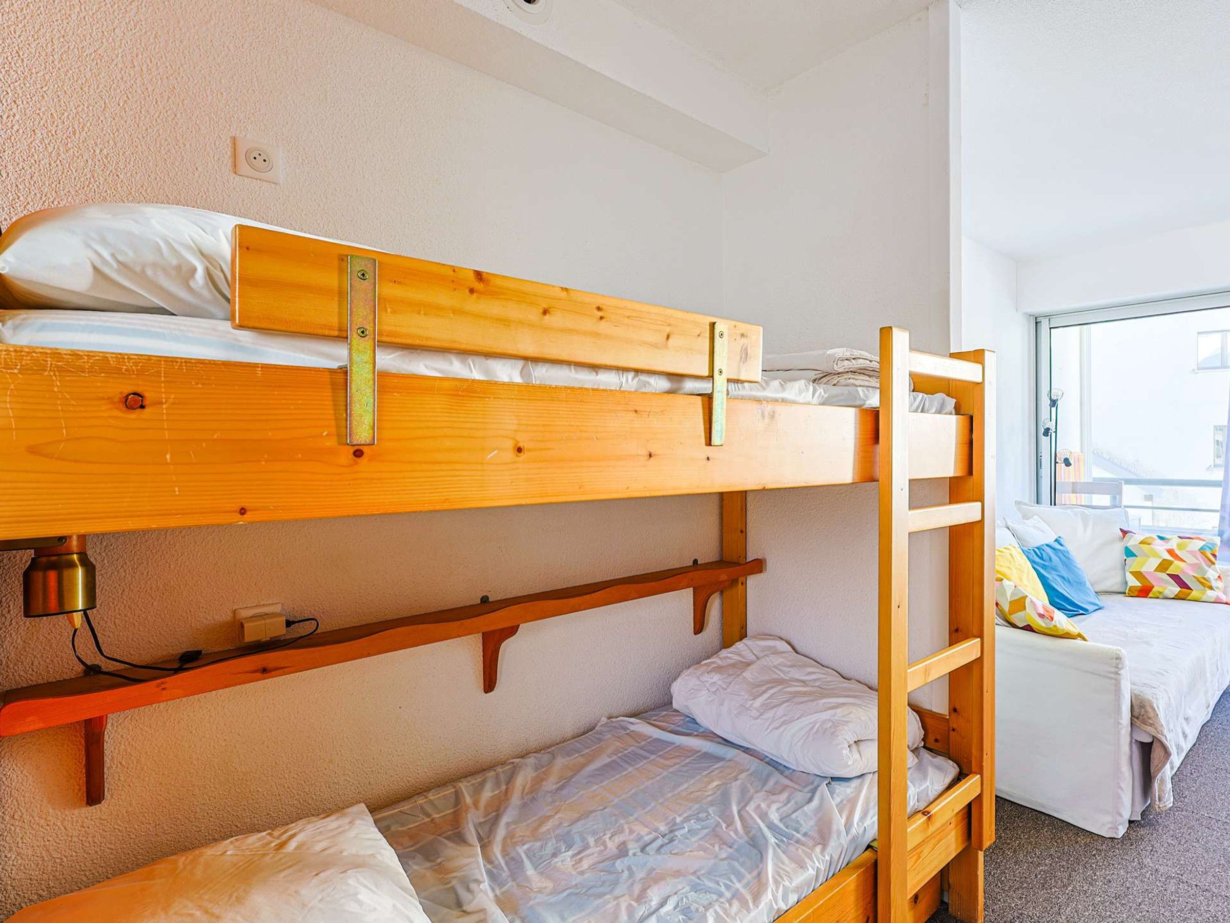 A bunk bed room with a window, a desk, and a chair.