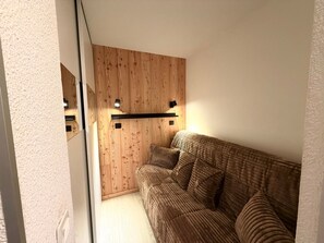 A room with a wooden wall, a sofa, and a light fixture. - Mountain studio tranquility, 5 guests (Vars)