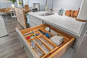 A kitchen with a drawer containing utensils, a coffee machine, and a sink.