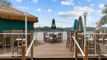 A deck with outdoor seating, a thatched-roof structure, and a view of the water.