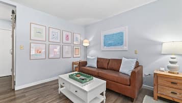 Un salon avec un canapé marron, une table basse blanche et des tableaux encadrés accrochés au mur.