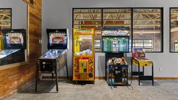 Une rangée de bornes d’arcade dans une pièce aux murs en bois, avec une fenêtre donnant sur l’extérieur.