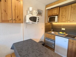 Eine kleine Küchenzeile mit Holzausstattung, einer Mikrowelle, einem Spülbecken und einem kleinen Kühlschrank.