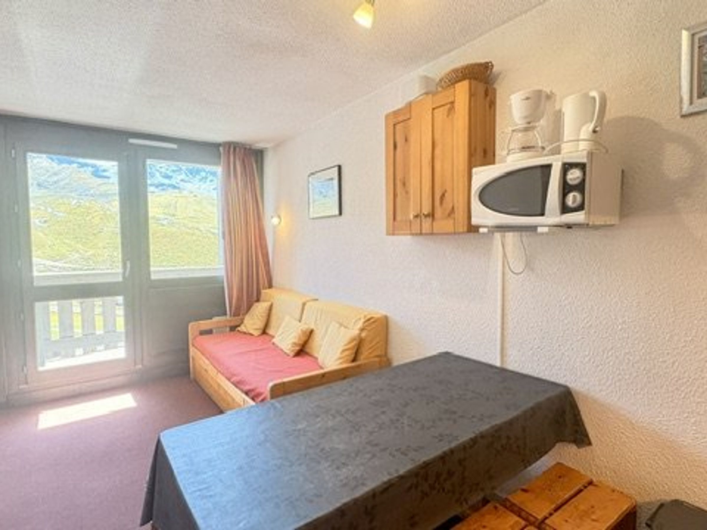 A room with a bed, a table, a microwave, and a cabinet.