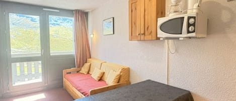 Une pièce comprenant un lit, une table, un four à micro-ondes et un placard.
