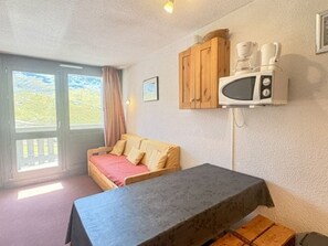 A room with a bed, a table, a microwave, and a cabinet. - Apartment with balcony - 4 guests, south view (Val Thorens)