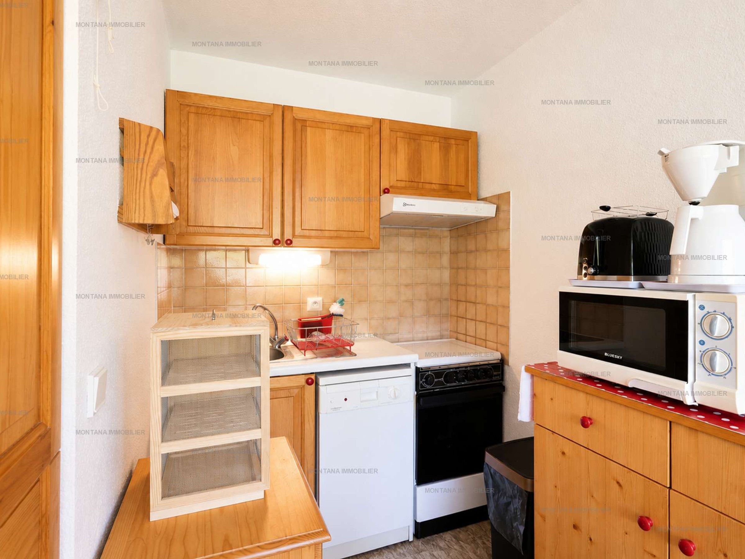 A compact kitchen with wooden cabinets, a white dishwasher, a black stove, and a microwave.
