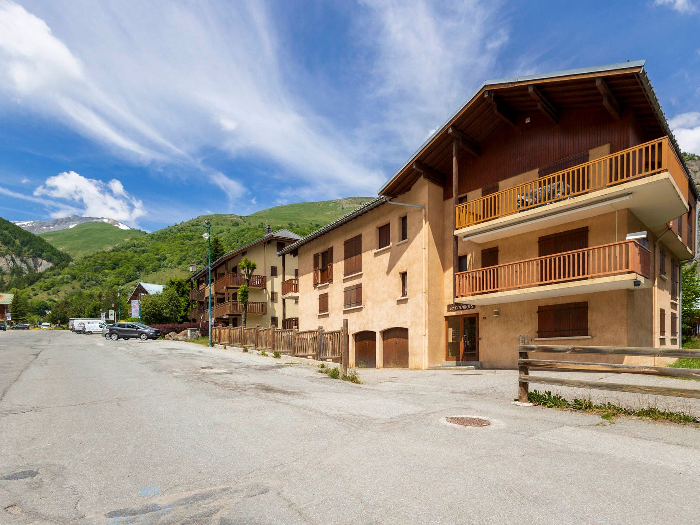 A multi-story hotel with balconies and a mountain backdrop.