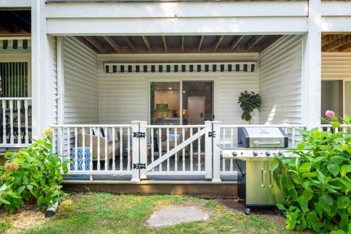 A porch with a grill and potted plants.