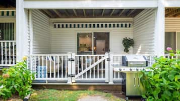 A porch with a grill and potted plants.