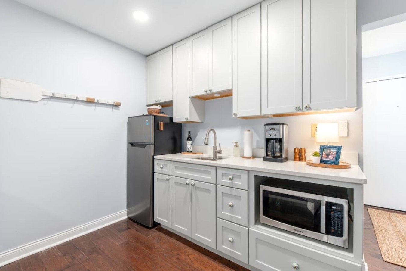 A kitchen with white cabinets, a built-in oven, a coffee maker, and a refrigerator.