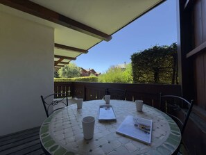An outdoor patio with a round table, four chairs, and a white umbrella. - Practical apartment, private parking - 6 guests (Praz-sur-Arly)