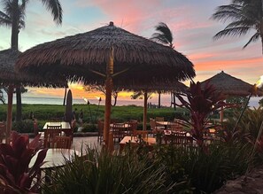 Ein Hotel am Strand mit Strohdächern und Holzmöbeln.