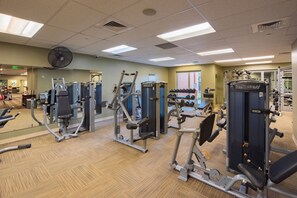 Une salle de sport équipée de divers appareils d’exercice, d’un ventilateur et d’un miroir.