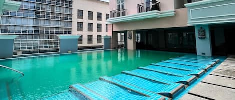 A swimming pool with clear water, surrounded by buildings with balconies and windows.