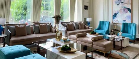 A spacious living room with a large window, a sofa set, a coffee table, and a blue armchair.