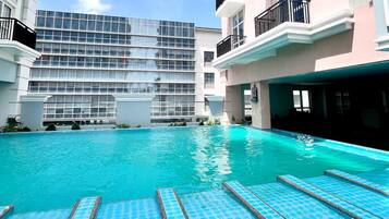 A swimming pool with clear blue water, surrounded by buildings with balconies and a modern architectural style.