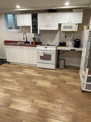 Eine Küche mit weißen Schränken, einem Herd, einer Mikrowelle und einem Spülbecken.