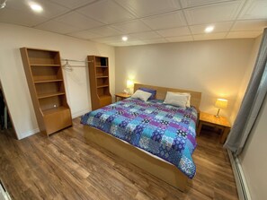 Ein Schlafzimmer mit einem hölzernen Bett, einem eingebauten Kleiderschrank, Nachttischlampen und einem Fenster mit Vorhängen.