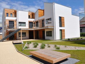 A modern multi-story residential building with a flat roof, large windows, and a wooden deck. - Holiday Apartment With 2 Bedrooms (Heiligenhafen)