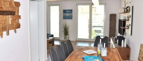 A dining area with a wooden table, chairs, and a hanging light fixture.