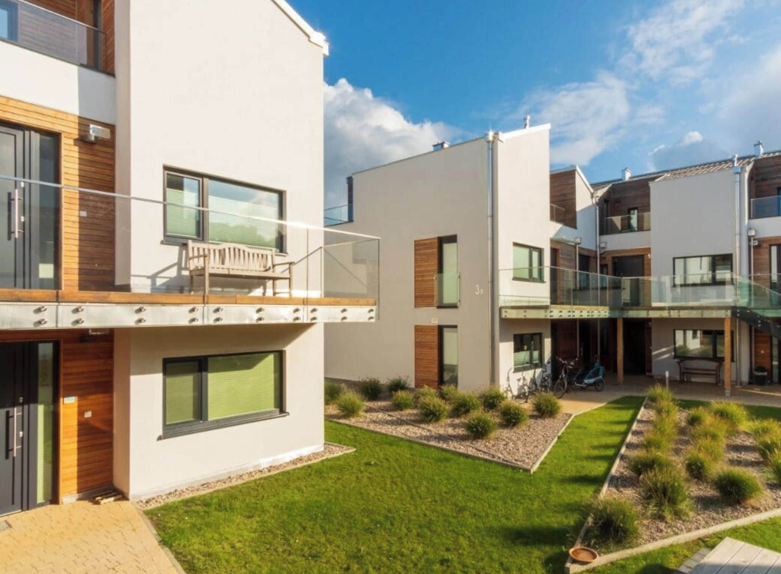 A modern residential building with a flat roof, large windows, and a balcony.