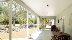 A covered patio with a table and chairs, a wooden fence, and a garden with trees and plants. - NEW | Wisteria Ranch | Perfect Round Top Escape (Round Top)