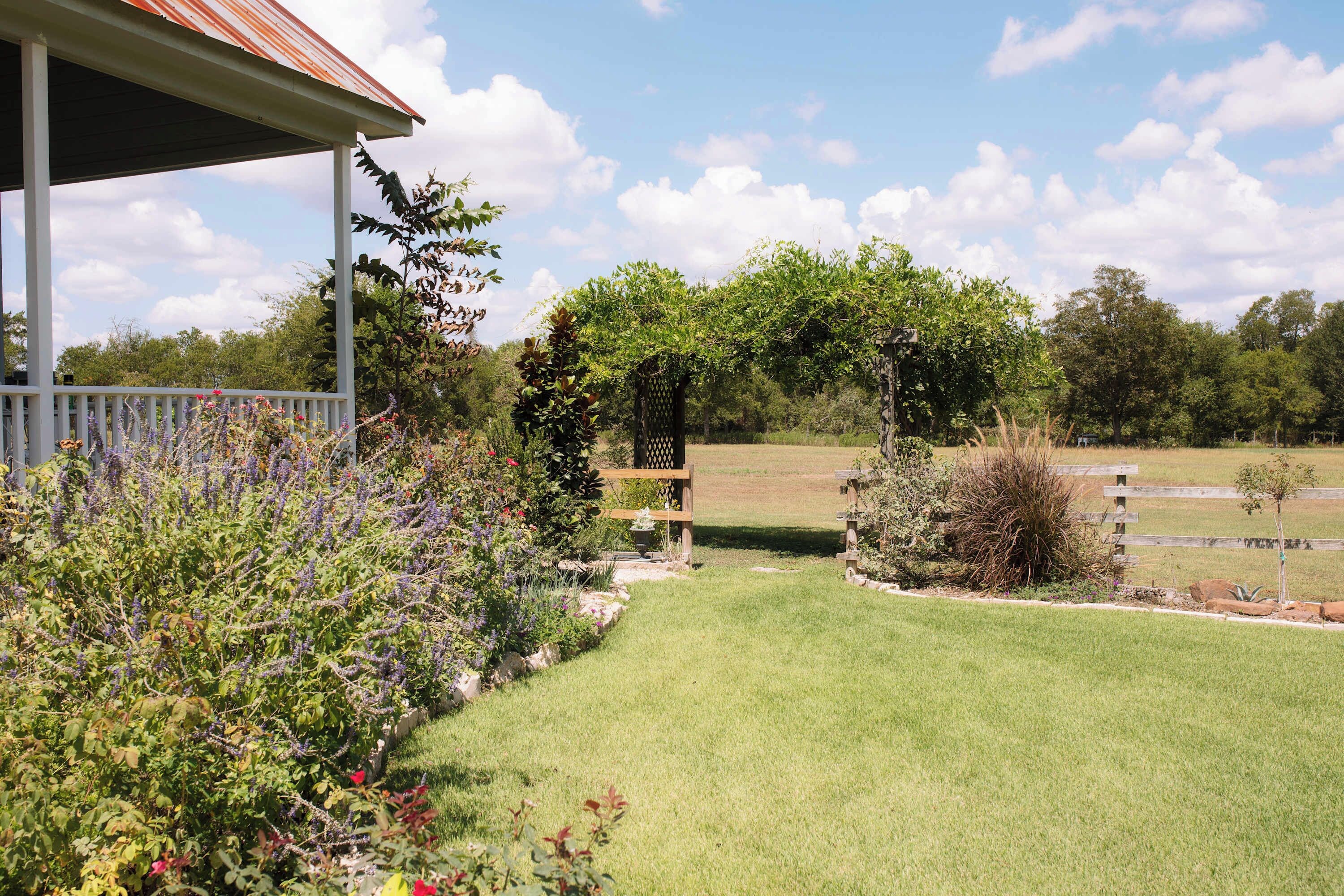 Eine überdachte Veranda mit Blick auf einen gepflegten Garten und ein Rasenfeld.