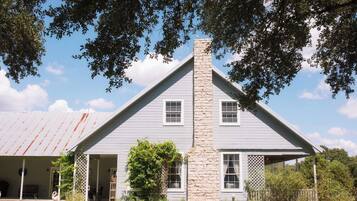 A two-story house with a stone chimney, white siding, and a covered porch.