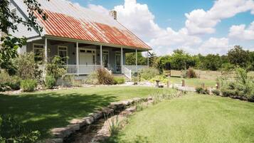 A house with a porch, a stone pathway, and a small stream.