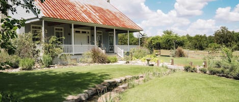 Une maison avec un porche, un chemin de pierres et un petit ruisseau.