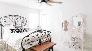 A bedroom with a bed, a bench, a dresser, a mirror, and a ceiling fan.