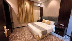 Ein Hotelzimmer mit Bett, Nachttisch, Klimaanlage, Tür und einem gemusterten Teppich.