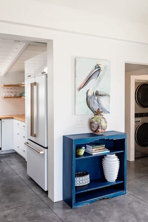 Eine moderne Küche mit weißen Schränken, einem blauen Akzentregal und einem Gemälde von einem Pelikan an der Wand.