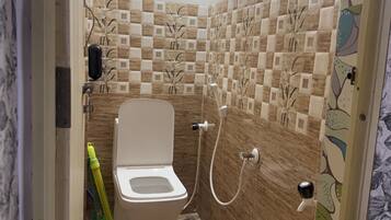 A bathroom with a toilet, shower, and decorative tiles.