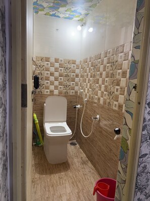 A bathroom with a toilet, shower, and decorative tiles. - Coconut Sooru Homestay Channapatna (Kurnagere)