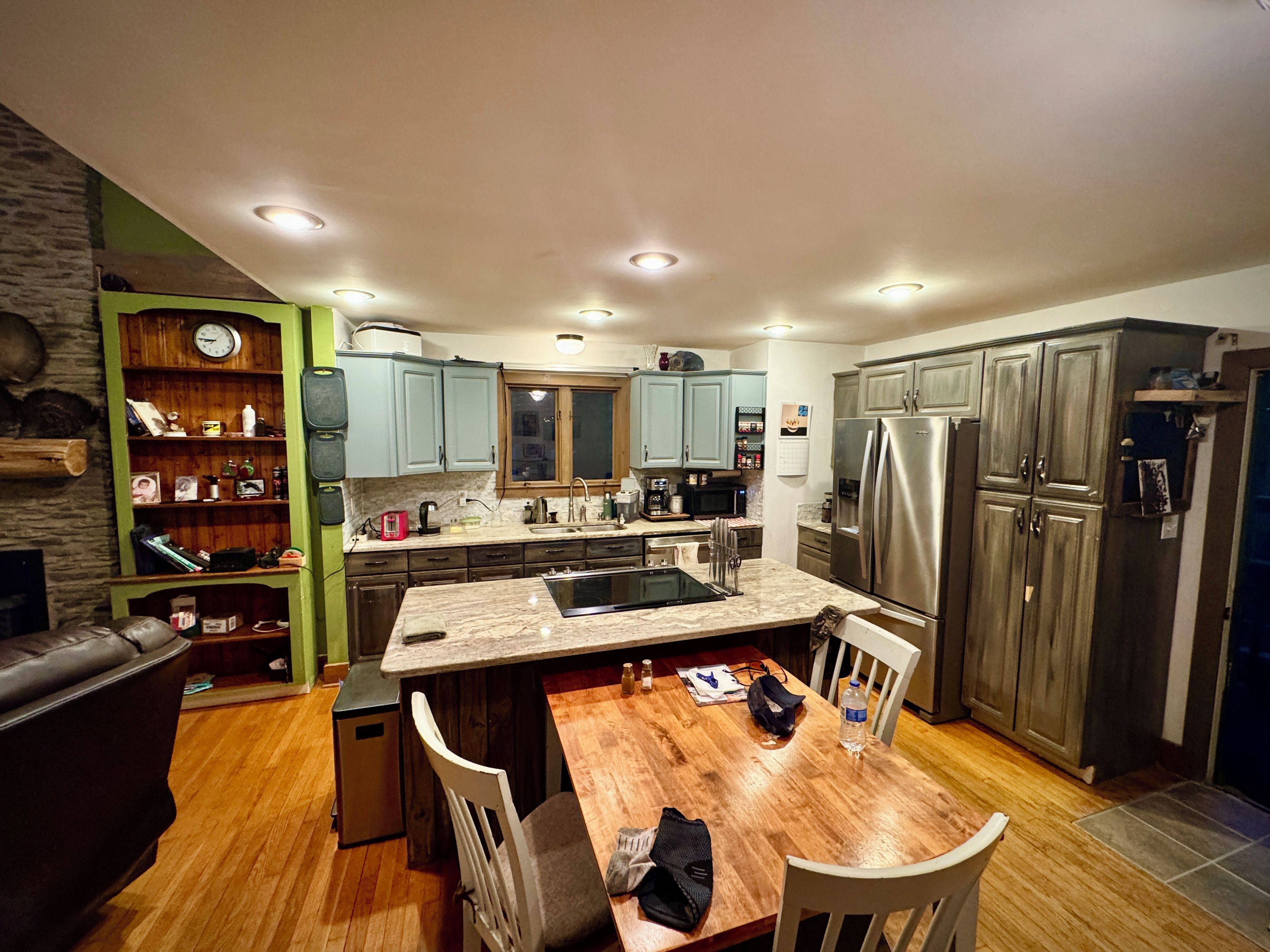 A modern kitchen with a central island, built-in appliances, and a dining area with chairs.