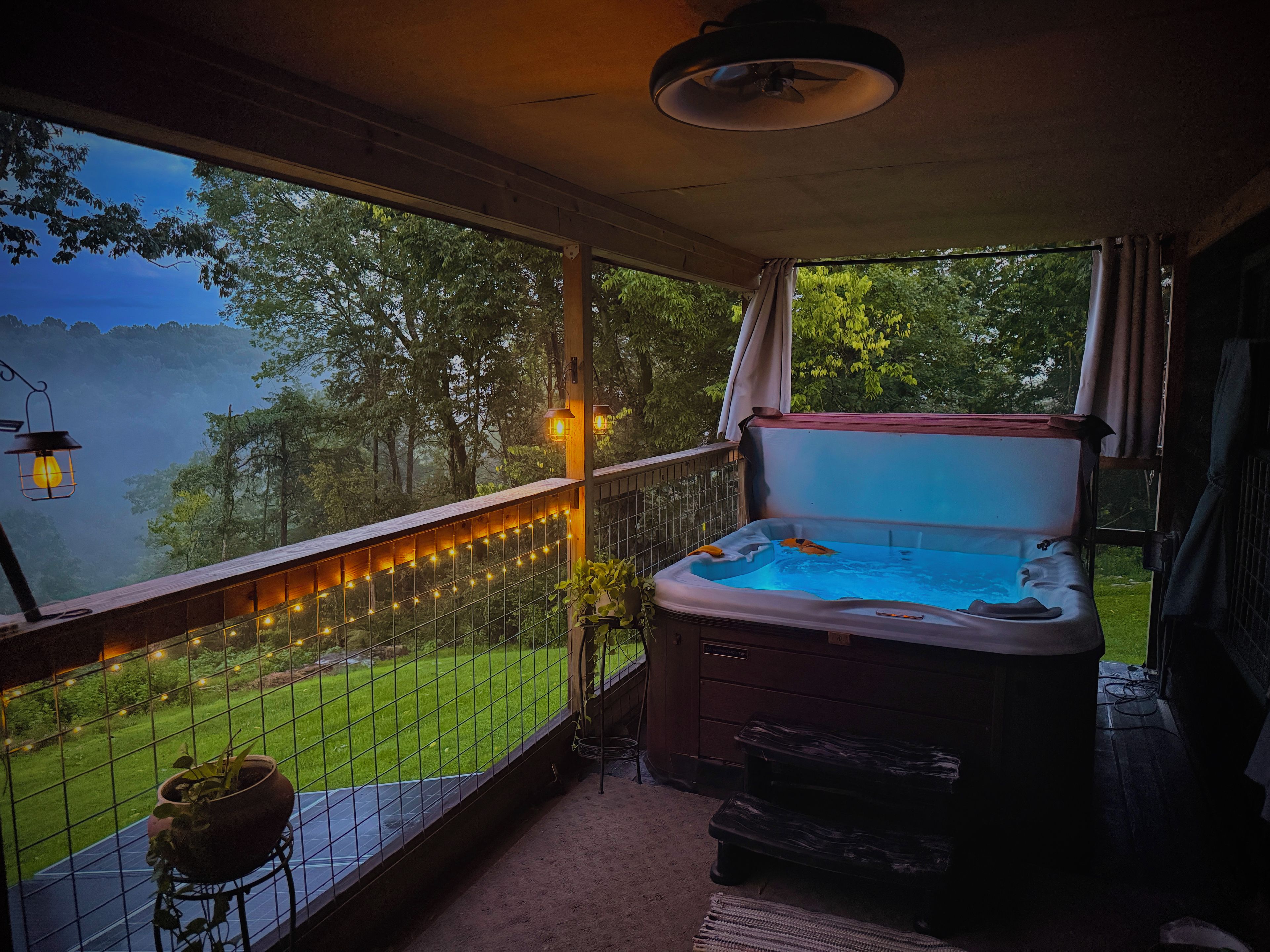 Banheira de hidromassagem com vista para um lago, um deck de madeira e luzes de Natal.