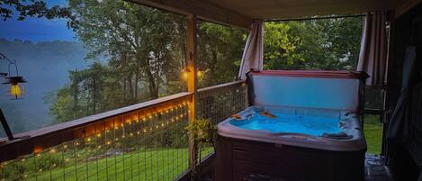 Banheira de hidromassagem com vista para um lago, um deck de madeira e luzes de Natal.