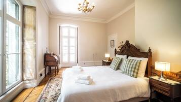 Una habitación de hotel con una cama grande, un escritorio, una silla y un ventanal.