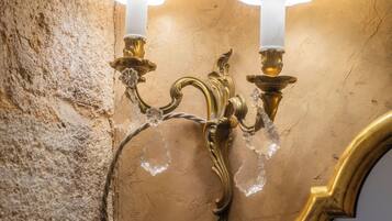 Een wandlamp met twee lampen, een structuurwand en een spiegel met gouden lijst.