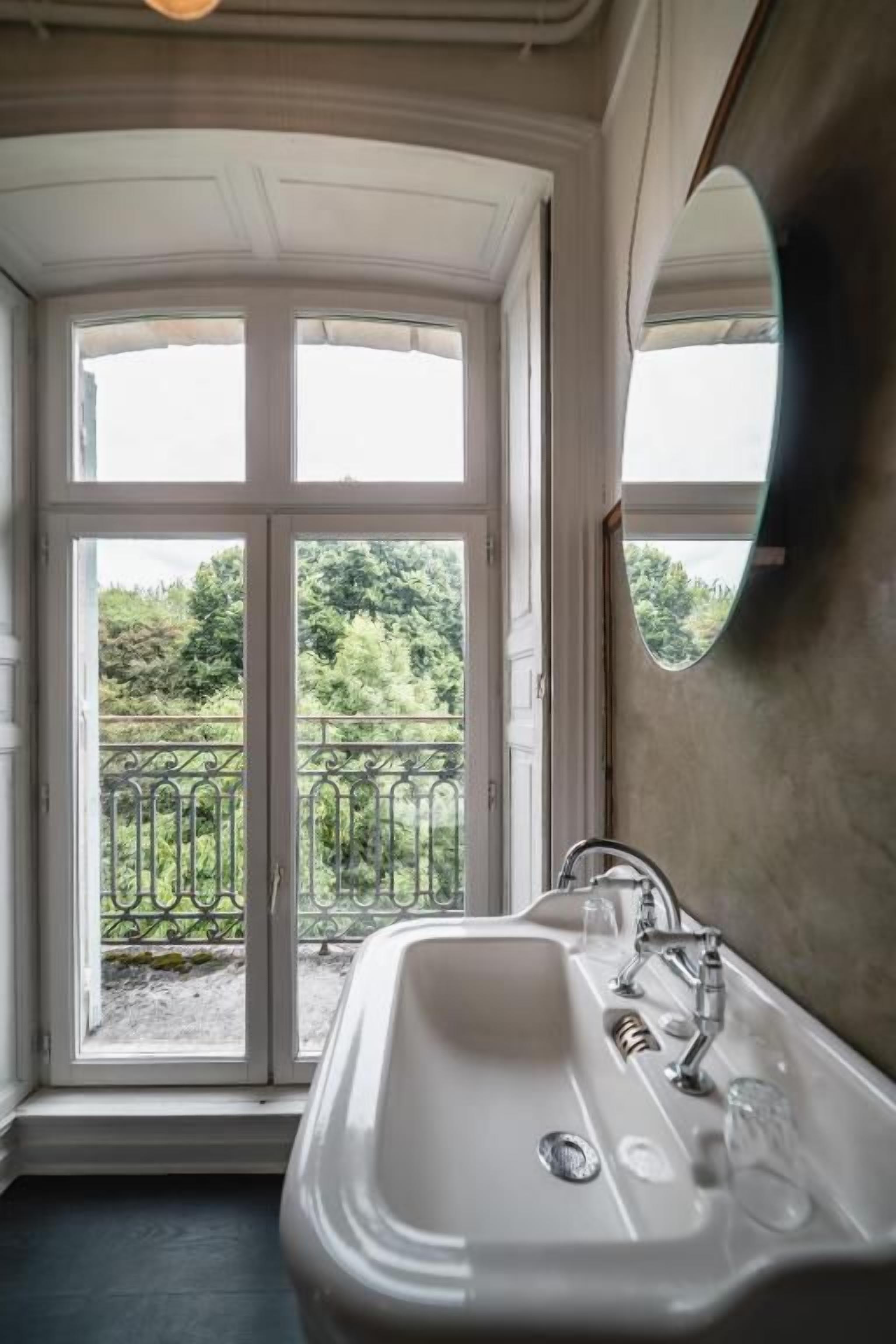 Une salle de bain avec une grande fenêtre, un lavabo et un miroir.