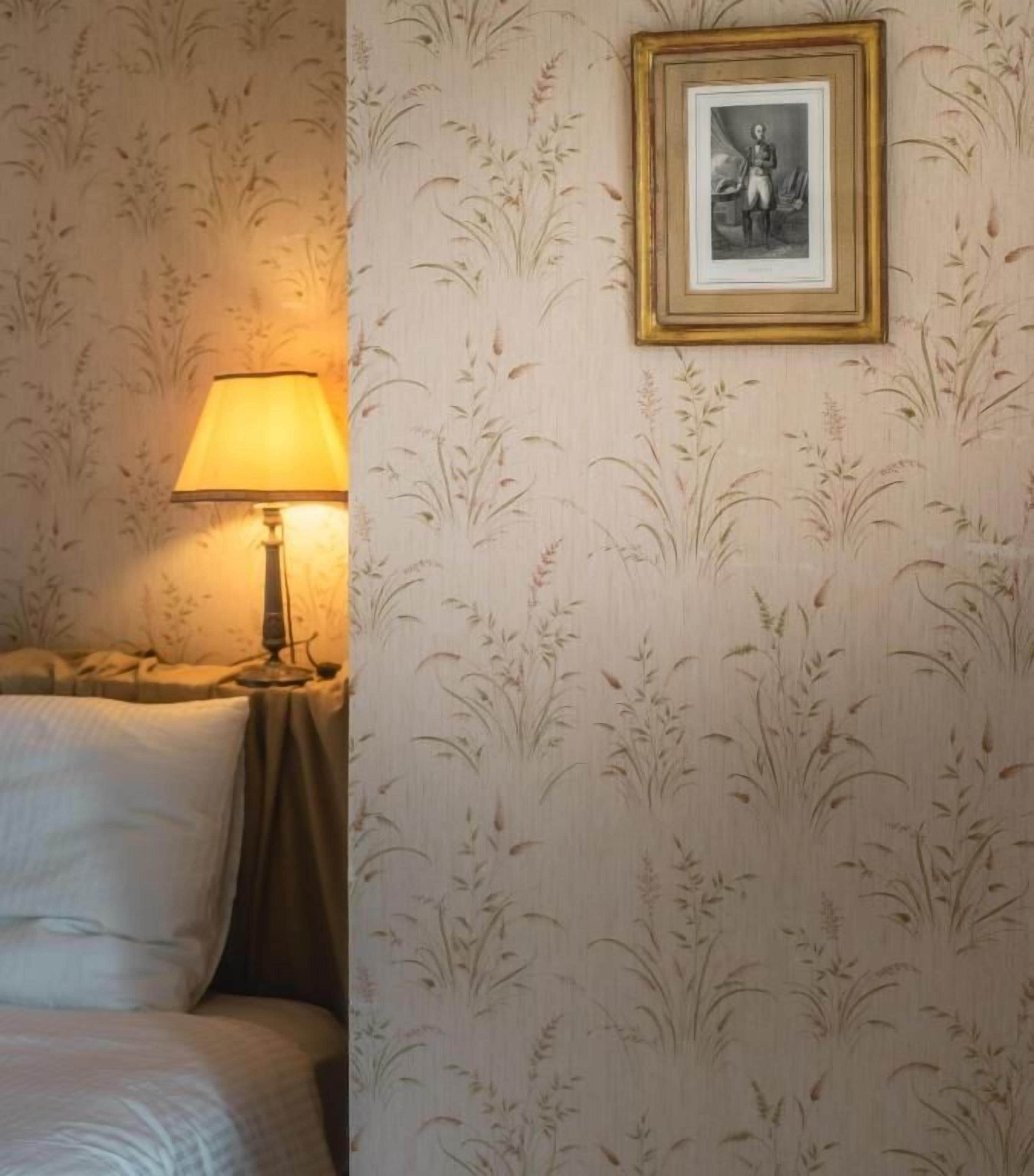 Ein Zimmer mit einem Bett, einem Nachttisch, einer Lampe und einem gerahmten Bild an der Wand.