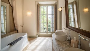 A bathroom with a bathtub, a sink, and a large mirror.